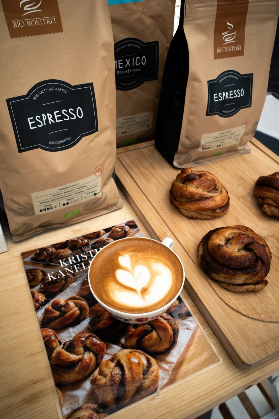 Cappuccino mit Latte Art neben Säcken mit Bio-Espressobohnen